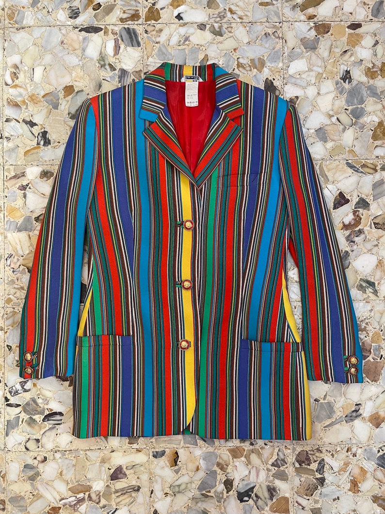 May include: A multi-colored striped blazer with a red lining and gold buttons. The blazer has a classic cut and is made of a lightweight fabric.