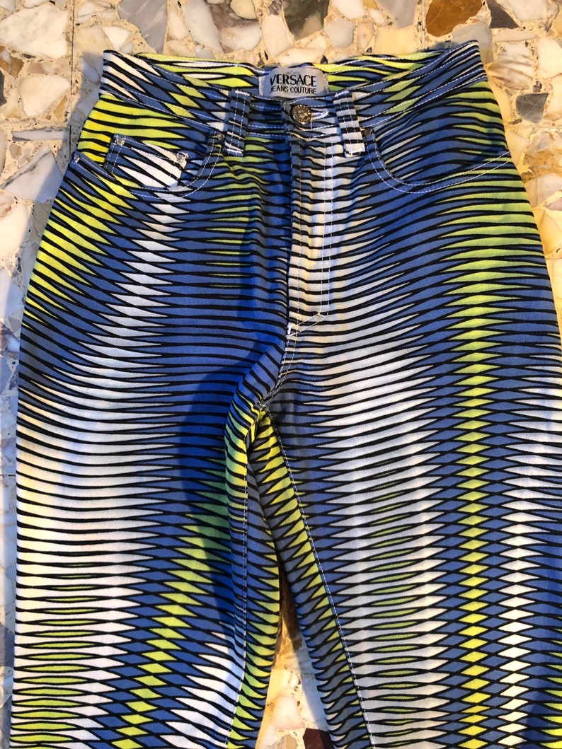 Puede incluir: Vaqueros con estampado azul, blanco y amarillo con el texto "VERSACE JEANS COUTURE" en la parte posterior de la cintura.