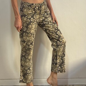 May include: A pair of brown wide-leg jeans with a floral print in shades of beige and white.