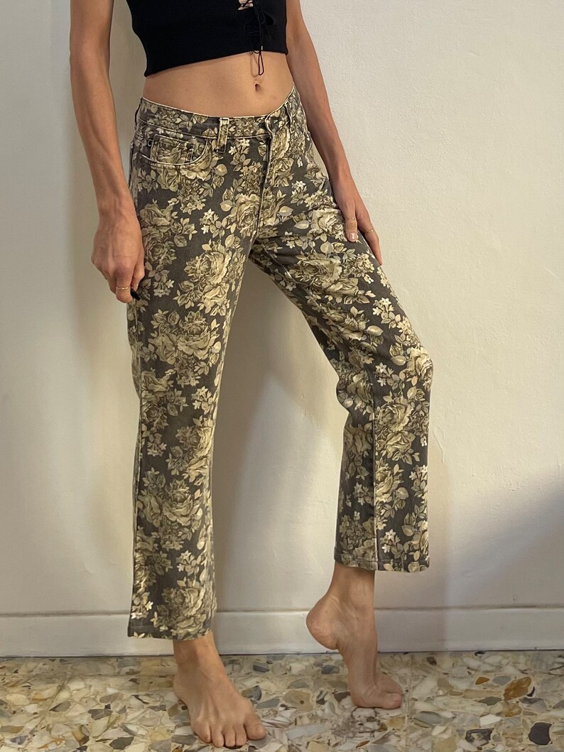 May include: A pair of brown wide-leg jeans with a floral print in shades of beige and white.