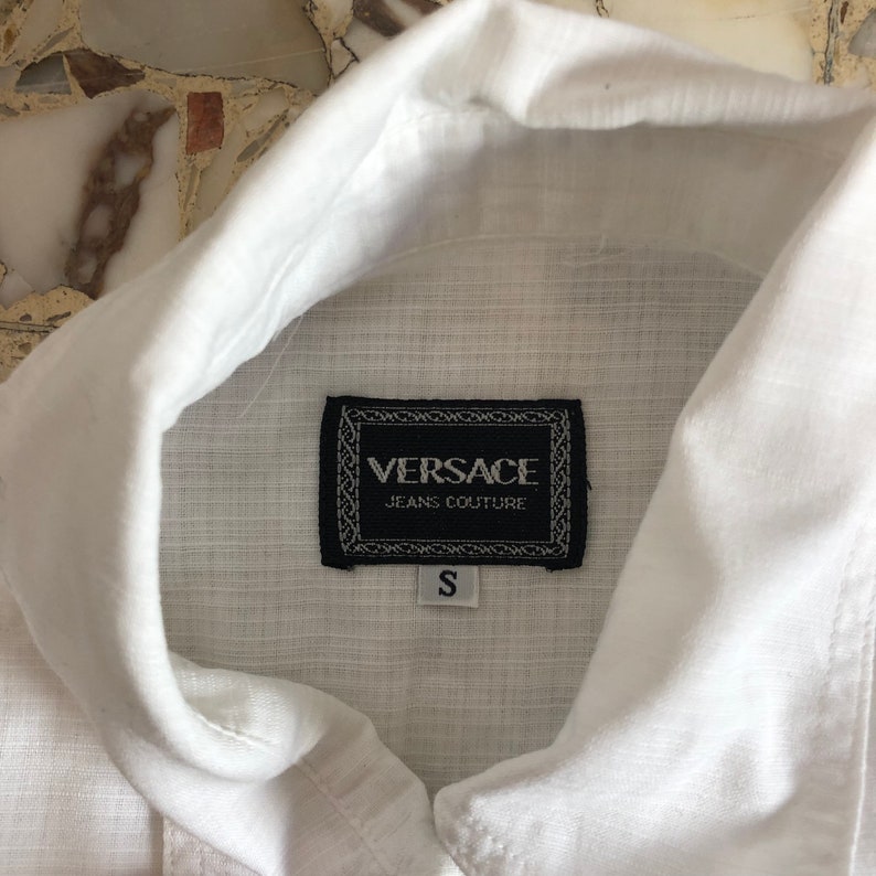 May include: White linen shirt with a black Versace Jeans Couture label and a size S tag.