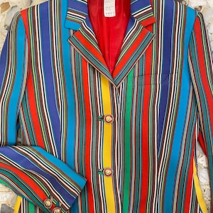May include: A long-sleeved blazer with a colorful striped pattern in shades of red, blue, yellow, green, and black. The blazer has gold lion head buttons.