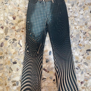 Puede incluir: Vaqueros negros y azules con un dise&ntilde;o ondulado abstracto. Los vaqueros tienen un corte recto.
