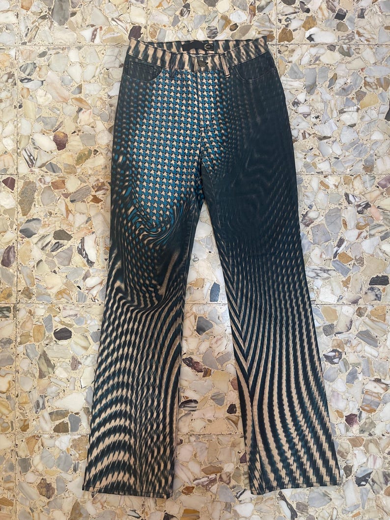 Puede incluir: Vaqueros negros y azules con un dise&ntilde;o ondulado abstracto. Los vaqueros tienen un corte recto.