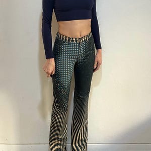 Puede incluir: Un pantal&oacute;n de pierna ancha con estampado negro y verde. El pantal&oacute;n tiene un patr&oacute;n geom&eacute;trico con un brillo sutil.