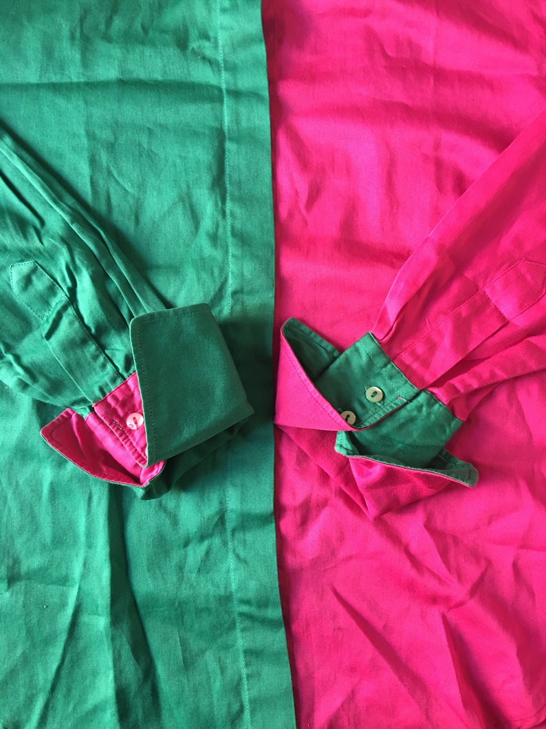 Puede incluir: Una camisa de manga larga con un dise&ntilde;o de bloques de color verde y rosa. La camisa tiene un cuello abotonado y pu&ntilde;os abotonados.