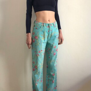 May include: A pair of light blue jeans with a floral print. The jeans have a straight leg and a high waist.