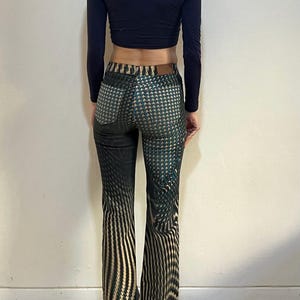 Puede incluir: Pantal&oacute;n acampanado de patr&oacute;n negro y verde con un dise&ntilde;o geom&eacute;trico. El pantal&oacute;n tiene cintura alta y pierna ancha.