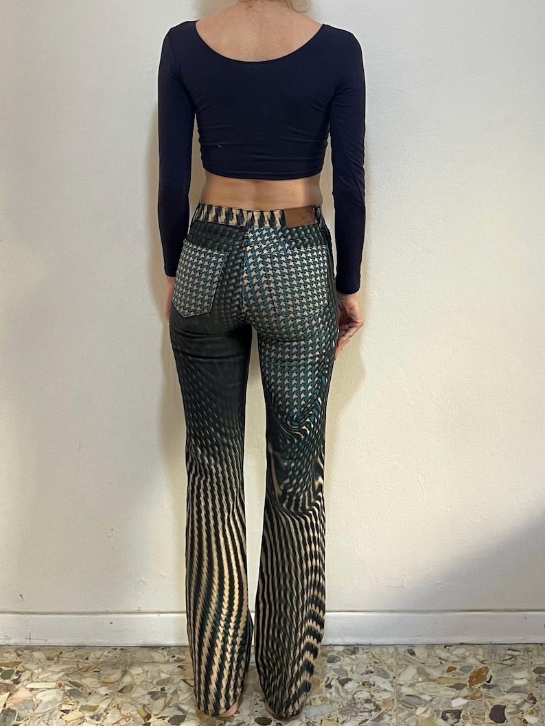 Puede incluir: Pantal&oacute;n acampanado de patr&oacute;n negro y verde con un dise&ntilde;o geom&eacute;trico. El pantal&oacute;n tiene cintura alta y pierna ancha.