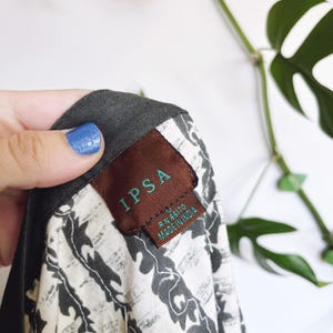 May include: Close-up of a garment label with the brand name "IPSA" in green embroidery on a brown tag. The label also includes "RN 66170 MADE IN INDIA". The fabric has a black and white floral pattern.