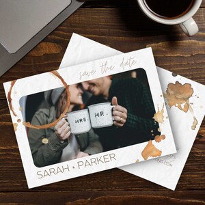Könnte beinhalten: Save-the-Date-Karte mit einem Kaffeefleck-Design. Die Karte zeigt ein Foto eines Paares, das Kaffeetassen hält, auf denen "Mr." und "Mrs." steht. Der Text "Save the date" und "Sarah + Parker" ist auf der Karte gedruckt.