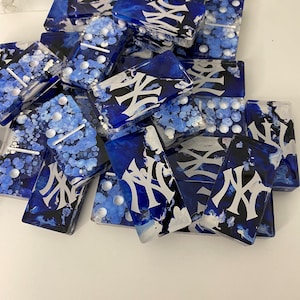 May include: A set of blue and white dominoes with a black and white "NY" logo on each tile. The dominoes are hand-painted with a unique marbled effect.
