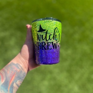 May include: A green and purple glitter tumbler with a black witch's hat and the text "Witch's Brew".