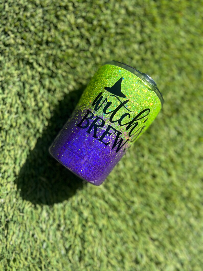 May include: A green and purple glitter tumbler with the text "witch's brew" and a black witch's hat graphic.