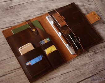 May include: A brown leather portfolio with multiple pockets and slots for carrying cards, a phone, a passport, and a tablet. The portfolio is open and the interior is visible.