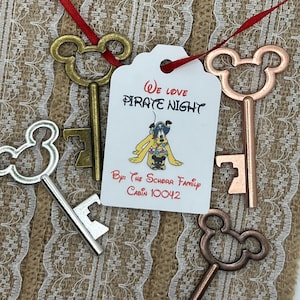 May include: Four gold-toned Mickey Mouse shaped key bottle openers with a white tag that says "We love Pirate Night" and "By: The Scheer Family Cabin 10042".