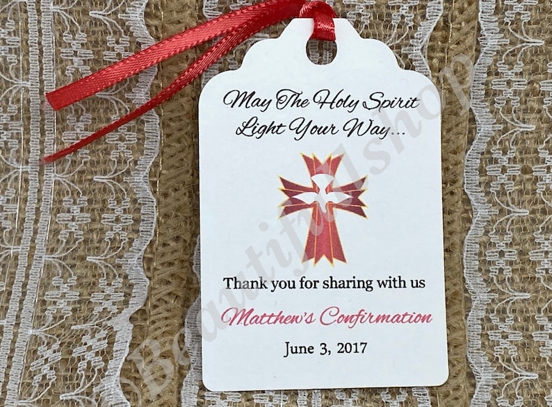 May include: White tag with red ribbon, featuring a red and gold cross with a white dove inside. The text reads "May The Holy Spirit Light Your Way... Thank you for sharing with us Matthew's Confirmation June 3, 2017".