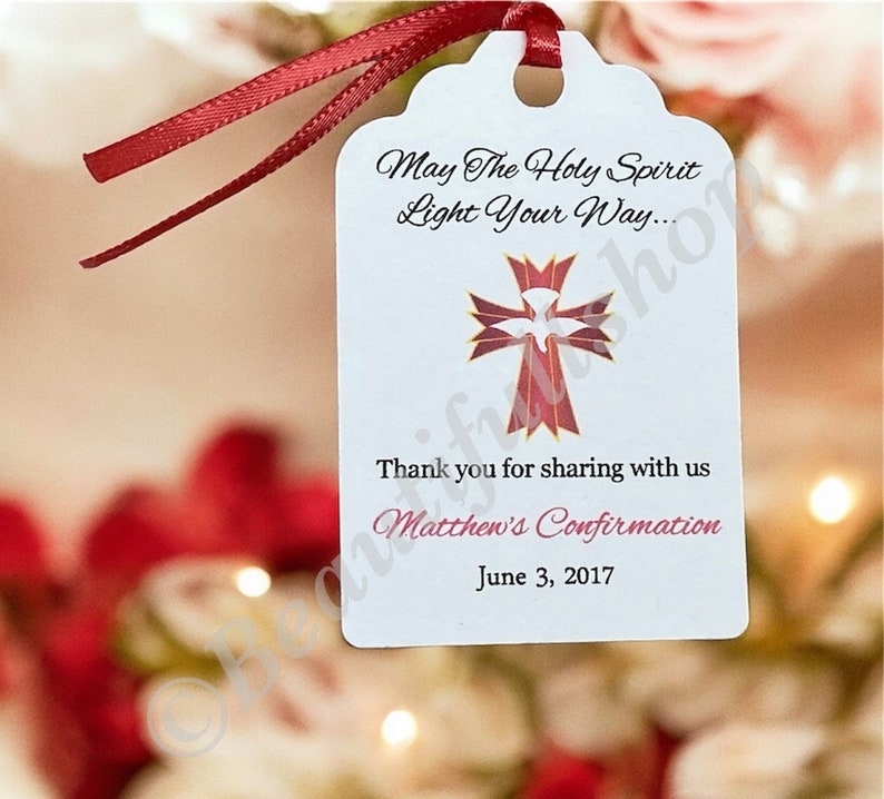 May include: White favor tag with a red ribbon. The tag features a red and gold cross with a white dove inside. The text reads "May The Holy Spirit Light Your Way... Thank you for sharing with us Matthew's Confirmation June 3, 2017"