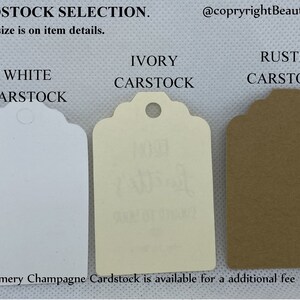 May include: Three cardstock tags in white, ivory, and rustic brown. The tags are shaped like a traditional gift tag with a scalloped edge and a hole at the top for string. The text "CARDSTOCK SELECTION" is at the top of the image. The text "WHITE CARSTOCK", "IVORY CARSTOCK", and "RUSTIC CARSTOCK" is below each tag. The text "++Shimmery Champagne Cardstock is available for an additional fee" is at the bottom of the image.