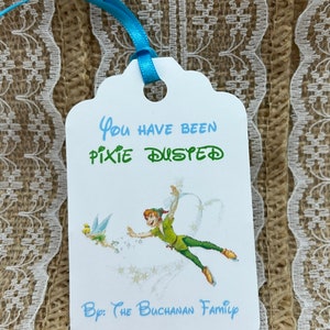 May include: White tag with blue ribbon, featuring Peter Pan and Tinkerbell flying. The tag reads "You have been pixie dusted" and "By: The Buchanan Family".