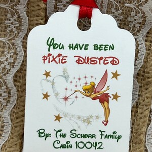May include: White tag with green text that reads "You have been pixie dusted" with a cartoon image of Tinkerbell sprinkling pixie dust. The tag also has green text that reads "By: The Schorr Family Cabin 10042".