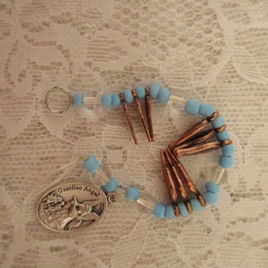May include: A blue and clear beaded charm bracelet with a silver charm that says "Guardian Angel". The bracelet has copper accents.