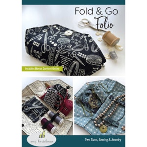 May include: A black and white fabric folio with a sewing theme. The folio is folded open to show the interior, which is lined with a patterned fabric. The folio is designed to hold sewing supplies, such as needles, thread, and scissors. The text "Fold & Go Folio" is printed on the front of the folio. The text "Includes Bonus Content Online" is printed on the bottom of the folio.