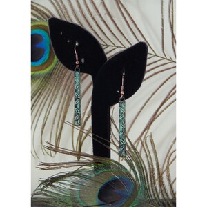May include: A pair of dangle earrings with a copper wire and a green rectangular pendant with a floral design.