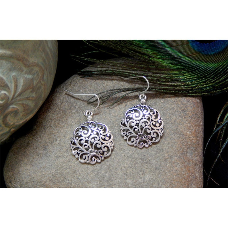K&ouml;nnte beinhalten: Silberne Filigranoh&auml;nger mit kreisf&ouml;rmigem Design. Die Ohrringe h&auml;ngen an einem silbernen Haken.