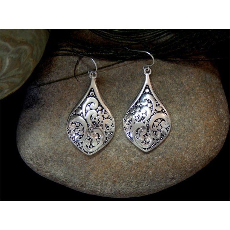 K&ouml;nnte beinhalten: Ein Paar silberne Ohrh&auml;nger mit filigranem Design. Die Ohrringe sind tropfenf&ouml;rmig und haben ein zartes, filigranes Muster.