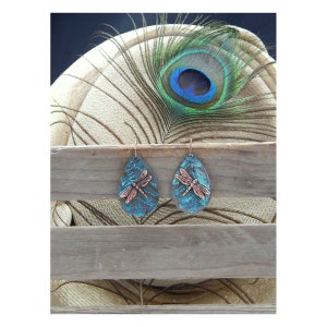 May include: Teal blue teardrop shaped earrings with a copper dragonfly design.