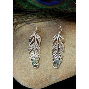 May include: Silver feather earrings with abalone shell accents. The earrings are dangling and have a delicate, intricate design.