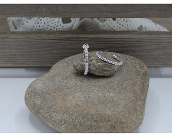 May include: A pair of silver hoop earrings with a row of clear rhinestones around the edge.