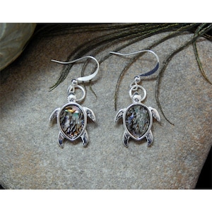 May include: A pair of silver dangle earrings featuring a turtle design with iridescent abalone shell accents.