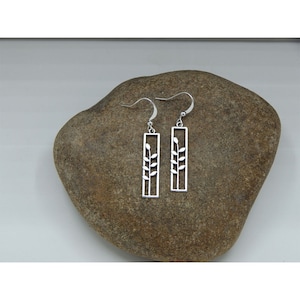 May include: A pair of silver dangle earrings with a rectangular design featuring a stylized branch with leaves.