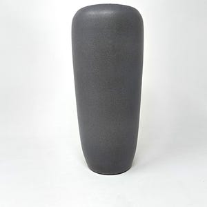 Op de afbeelding: Een hoge, donkergrijze keramische vaas met een textuuroppervlak. De vaas heeft een afgeronde bovenkant en een licht taps toelopende cilindrische vorm. De vaas heeft een neutrale kleur en zou veel interieurstijlen aanvullen.