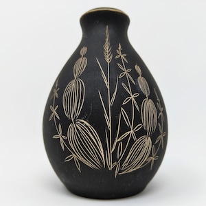 以下が含まれることがあります： クリーム色の花柄が施された、小さな黒い陶器の花瓶。花瓶は丸みを帯びたボディと細い首をしています。