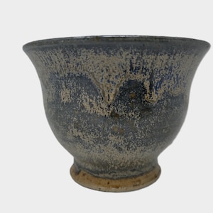 May include: A small, grey ceramic bowl with a speckled glaze. The bowl has a rounded bottom and a flared rim.