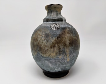 Puede incluir: Un pequeño jarrón redondo de cerámica gris y marrón con base negra. El jarrón tiene un cuello estrecho y una etiqueta que dice "Ruscha Art".