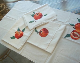May include: Set of four white cotton tea towels with hand-painted peach designs. The peaches are red and orange with green leaves.