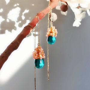 Może przedstawiać: Para kolczyków wiszących ze złotym łańcuszkiem i turkusowym, łzowym kamieniem. Kamień otoczony jest gromadą małych różowych koralików.