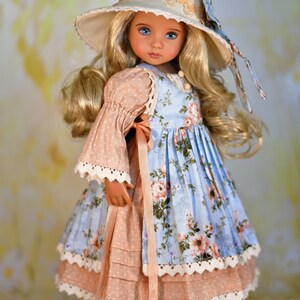 May include: A doll in a light blue floral dress with a peach sleeve and trim. The doll has blonde hair and a matching hat with a floral bow. The doll is wearing white shoes.
