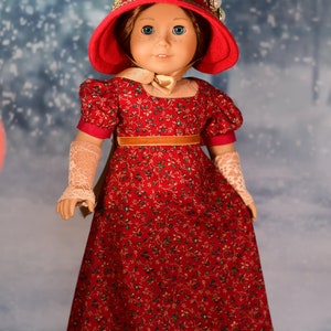 May include: A red dress with a floral pattern and gold trim. The dress is worn by a doll with a red hat and gold trim. The doll has blue eyes and a fair complexion.