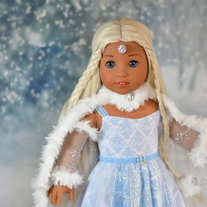 May include: A doll with long blonde braids wearing a blue and white dress with a white fur trim. She is wearing a silver tiara and a white fur collar.