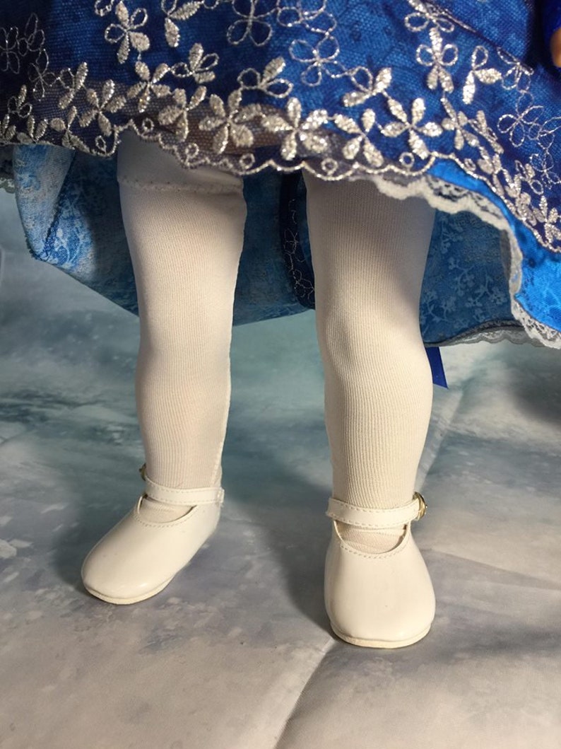 May include: White tights and white shoes with a buckle on a doll wearing a blue and silver dress.