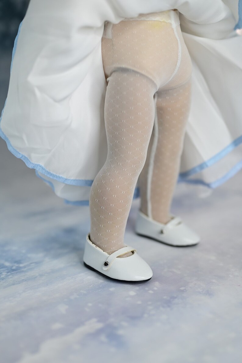 May include: White tights with a small polka dot pattern and white shoes with a black buckle.
