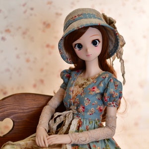 May include: A doll wearing a blue floral dress and a matching hat with a blue ribbon. The doll has long brown hair and is seated on a wooden bench. The dress features a floral pattern with red and pink roses.