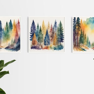 May include: Three watercolour paintings of a forest scene with tall trees in shades of blue, green, yellow, and orange. The paintings are framed in white and hung on a white wall.