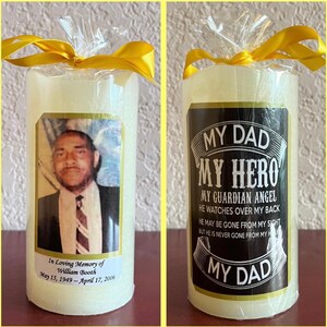 May include: A white pillar candle with a black and gold label that reads "My Dad My Hero My Guardian Angel He Watches Over My Back He May Be Gone From My Sight But He Is Never Gone From My Heart My Dad". The candle also has a photo of a man and the text "In Loving Memory of William Booth May 15, 1949 - April 17, 2006".