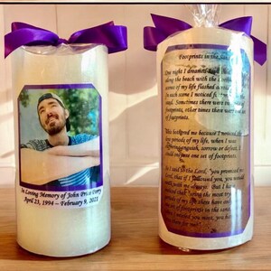 May include: Two white pillar candles with purple ribbon bows. One candle has a photo of a man and the text "In Loving Memory of John Price Perry April 23, 1994 - February 9, 2021". The other candle has the text "Footprints in the Sand" and a poem about footprints in the sand.